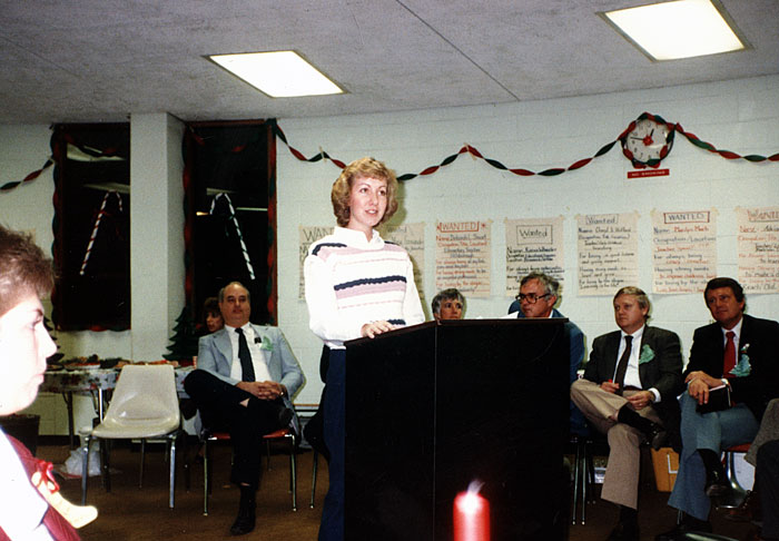 a woman at a podium speaking to a group of faculty