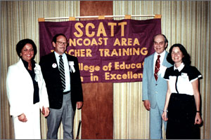 SCATT faculty standing in front of a SCATT flag