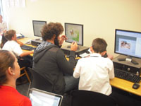 A Student teacher helping elementary students at computer workstations.